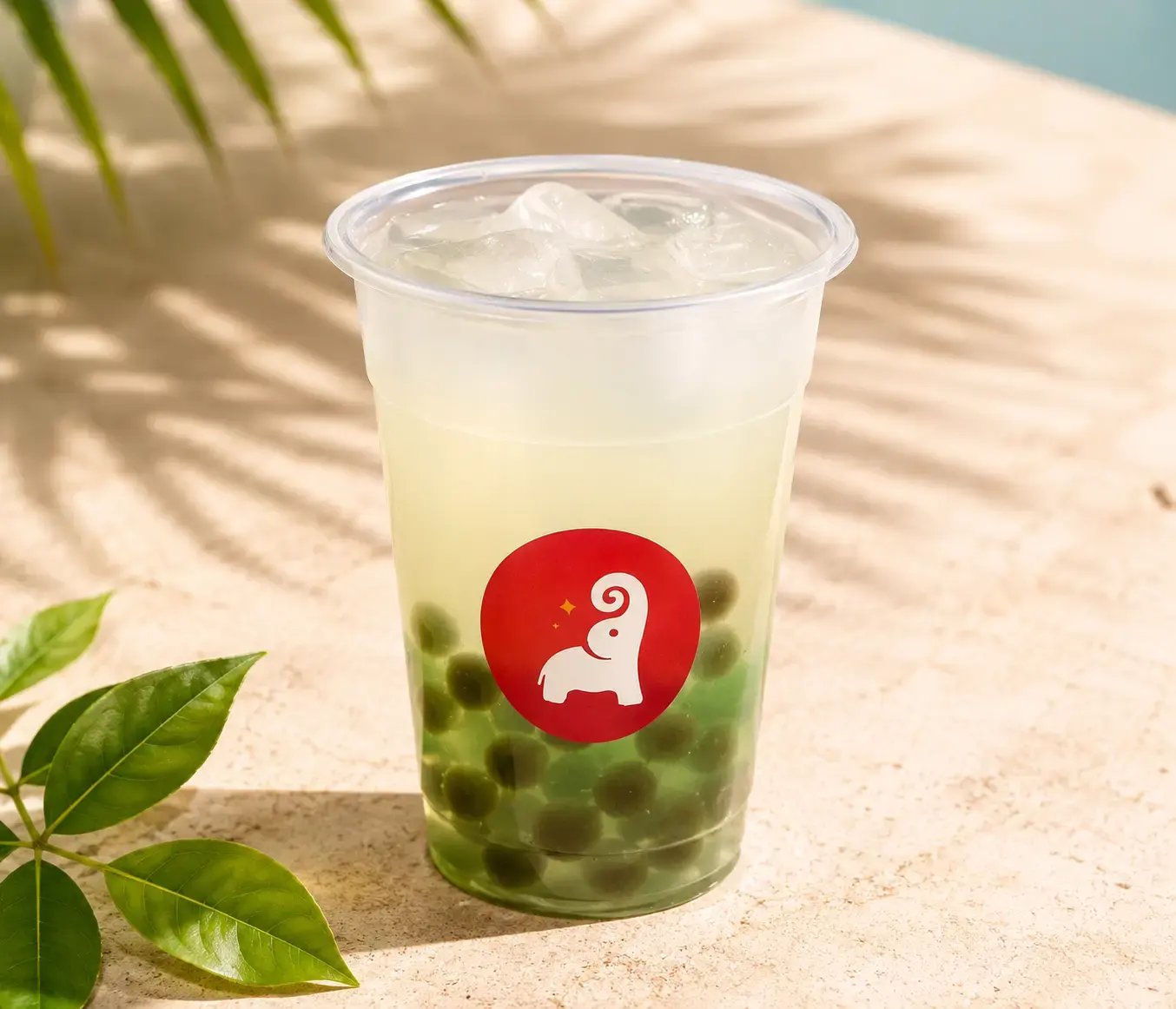 Tai Sweets bubble tea with green tapioca pearls in a cup with the Tai Sweets elephant logo